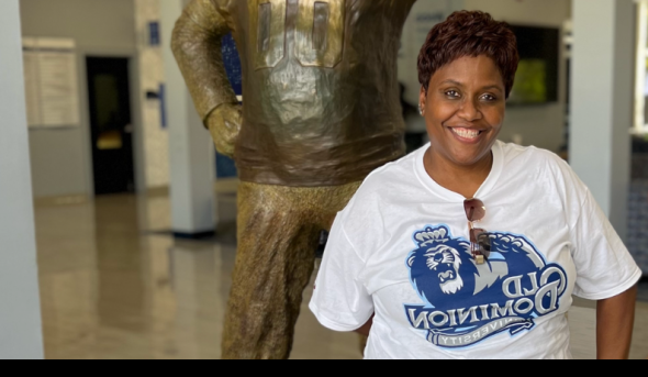 A woman stands in front of a statue of ODU's mascot.