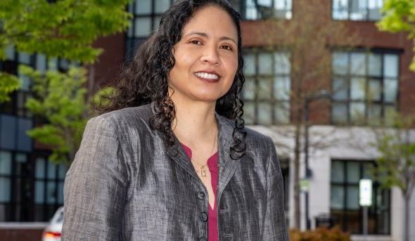 Headshot of woman smiling in front of an academic building