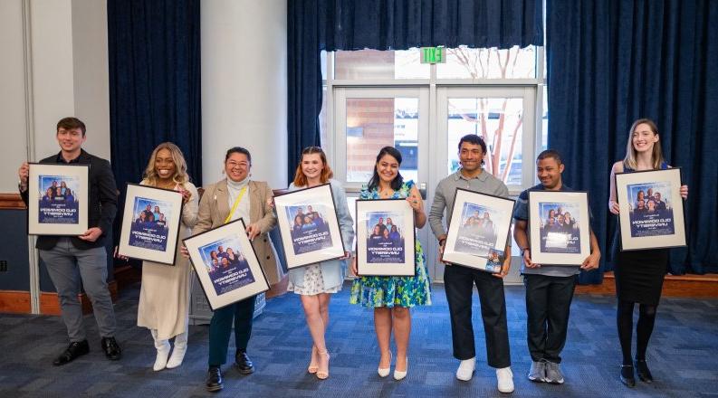 students standing while each holding a framed movie poster 