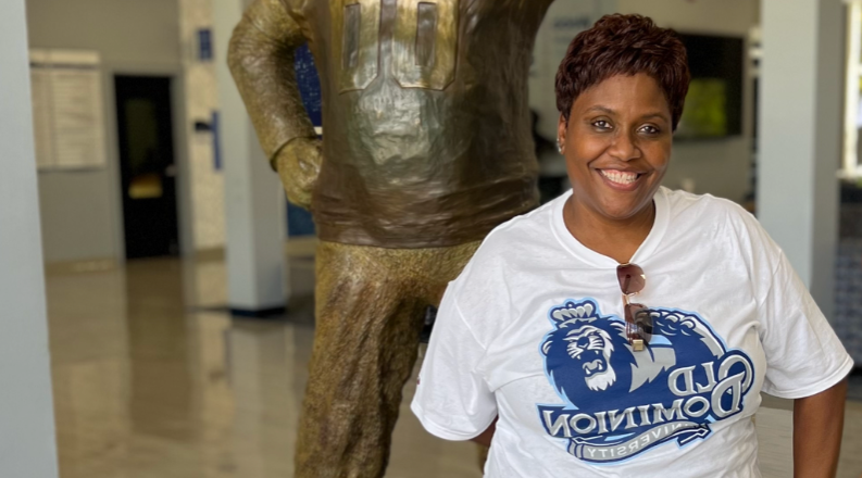 A woman stands in front of a statue of ODU's mascot.