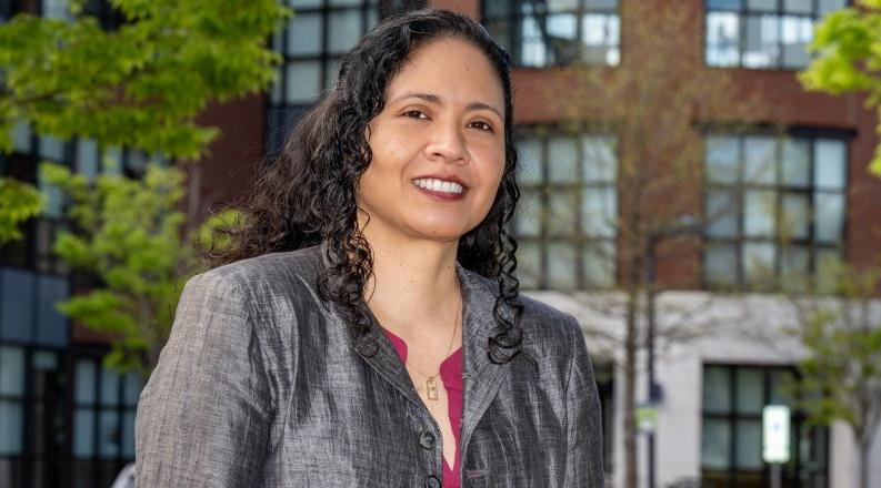 Headshot of woman smiling in front of an academic building