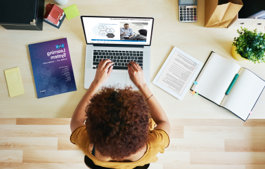 woman at desk typing on a laptop.