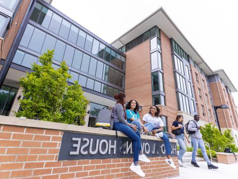 Students sitting and talking in front of Hugo Owens residence hall