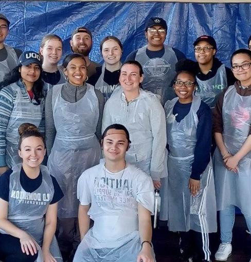 Group of 17 ODU students with plastic aprons; 14 students standing.