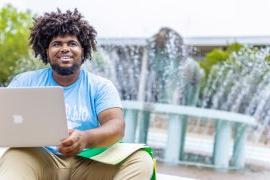 student sitting at the base of the lion fountain smiling